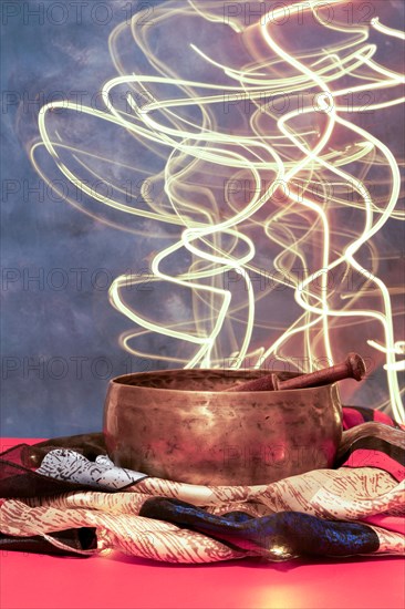 Tibetan singing bowl on colored cloth with moving led lights in the background