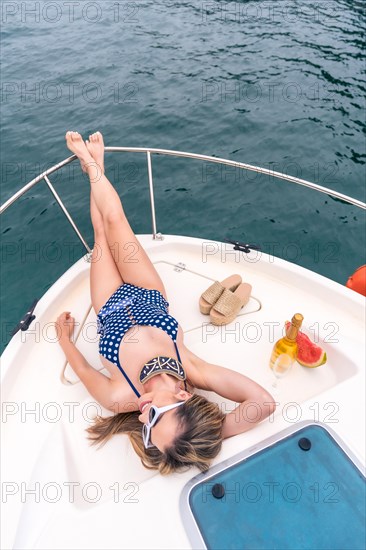 Top view of a young woman lying on the deck of a boat sunbathing