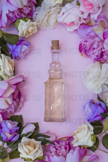 High angle view essential oil surrounded with fresh flowers pink background
