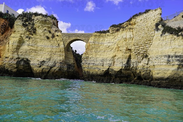 Historic Roman stone bridge at Praia da Batata beach in the rocky coast of Lagos