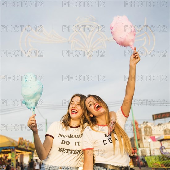 Two happy female friends holding candy floss