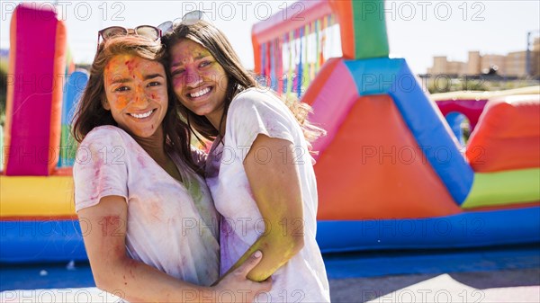 Close up happy young women with holi color their face embracing