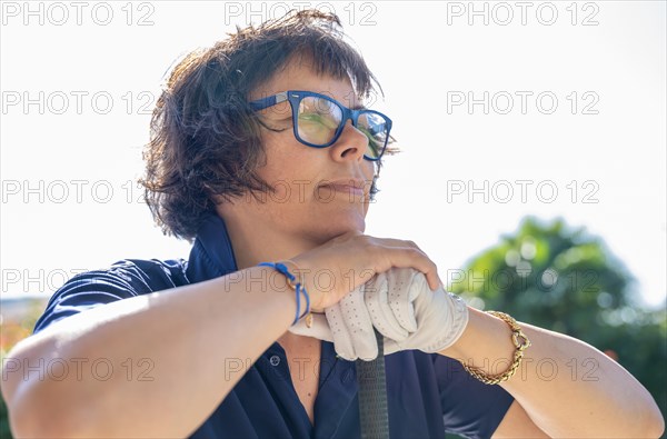 Female Golfer with a Glove Leaning on Her Golf Club in a Sunny Day in Switzerland