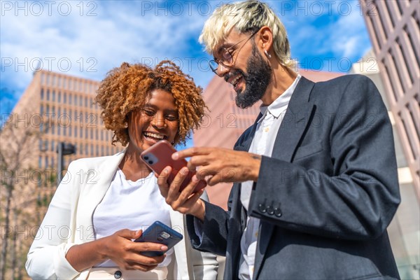 Close-up low angle view of two multi-ethnic smiling business people using phone in the street