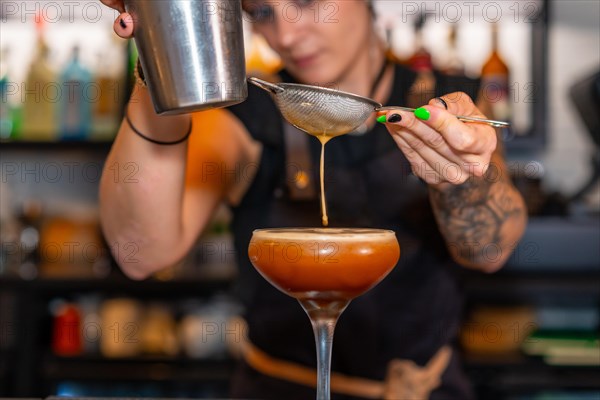 Professional bartender preparing an elegant cocktail in the counter of a bar