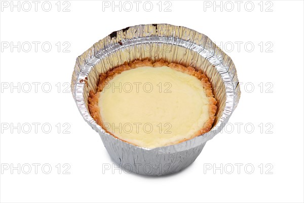 High angle view of vanilla cake in a baking foil dish isolated on white background