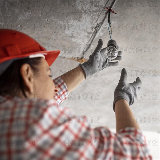 Low angle female construction worker with light bulb
