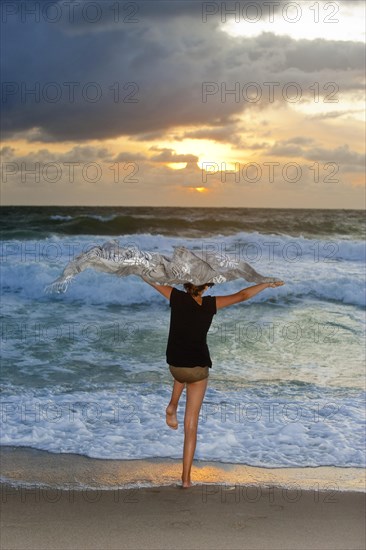 Girl on the beach of the North Sea with waves in the evening sun