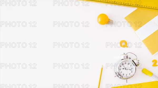 Alarm clock light bulb near assorted stationery
