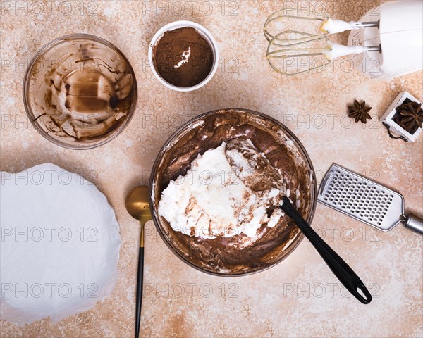 Electric food mixer hand grater star anise cocoa powder cake dough brown textured background