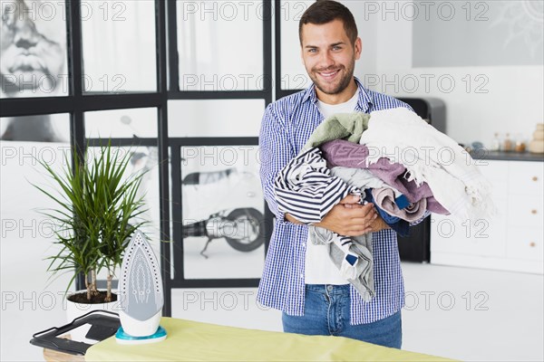 High angle man holding stack clothes