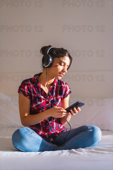 Vertical photo of a cute woman listening to music alone in the bed