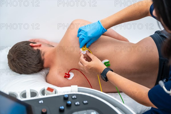 Nurse placing electrodes on the back of a cardiology patient during the cardiac test of the electrocardiogram