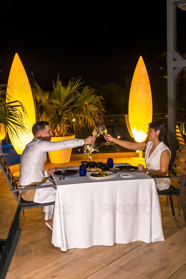 Vertical photo of a romantic couple toasting during an outdoors luxury dinner