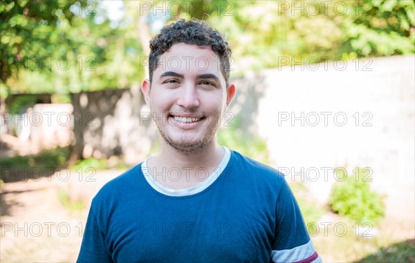 Portrait of Latin American man looking and smiling at the camera. Portrait of cheerful young latin guy smiling at camera outdoors