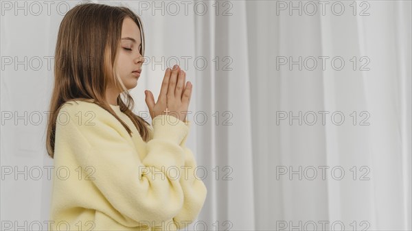 Side view little girl praying with copy space