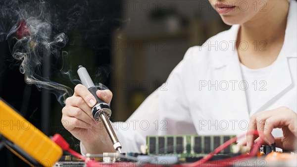 Female technician with soldering iron electronics board