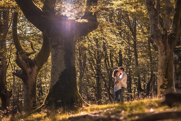 Wide view photo of lovers kissing standing in the middle of a forest