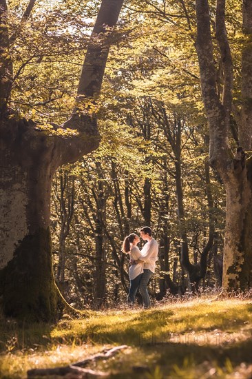 Vertical photo of a couple about to kiss embracing in the forest