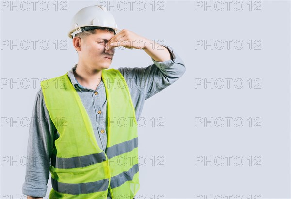 Man engineer covering her nose from a bad smell isolated isolated. Displeased young engineer holding her nose isolated