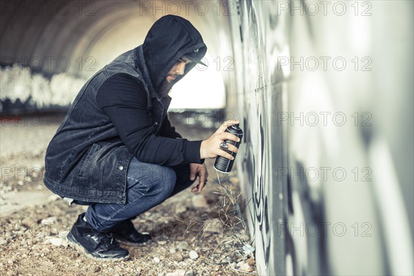 Side view man hoodie painting graffiti wall