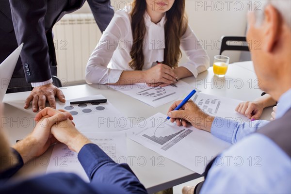 Close up mature businessman analyzing graph with his colleagues