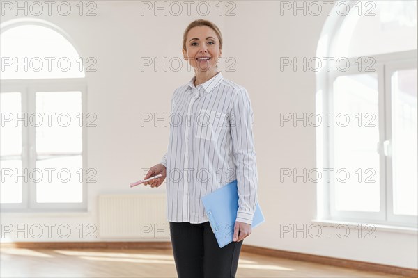 Front view smiley female realtor empty house