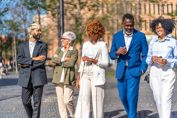 Elegant multicultural business people talking relaxed while walking along the city