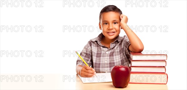 Happy young hispanic school boy at desk with books and apple isolated on a white background