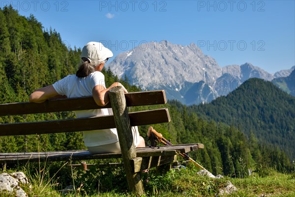 Hiker on a bench at the Mordaualm enjoying the view of the Watzmann