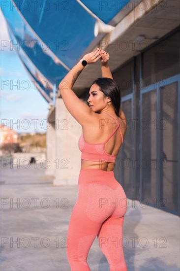 Rear view of a fitness model in modern sportive clothes in an urban park