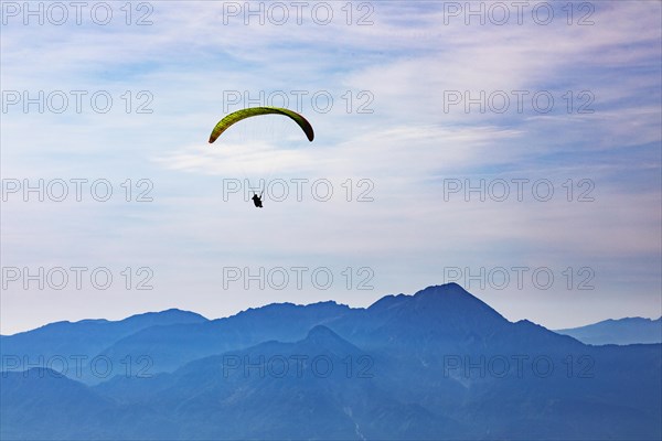 Paragliders high above the mountains with a view of the Klagenfurt basin and the Karawanken