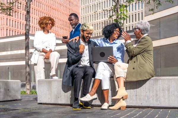 Business team using laptop and celebrating news from an online meeting outdoors