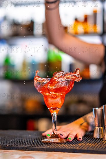 Vertical cropped photo of a unrecognizable bartender pouring ingredients into a glass in the counter of a bar