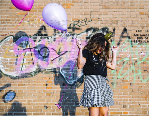 Girl holding balloons front graffiti wall