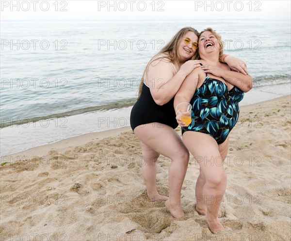 Happy plus size friends standing sand