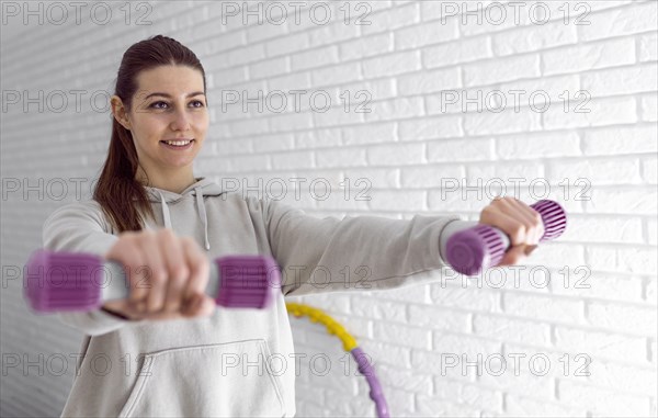 Medium shot smiley woman holding dumbbells