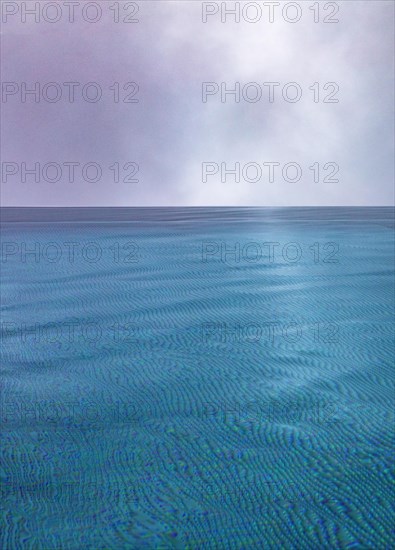 Rippled water surface during rain in swimming pool with dramatic cloudy sky