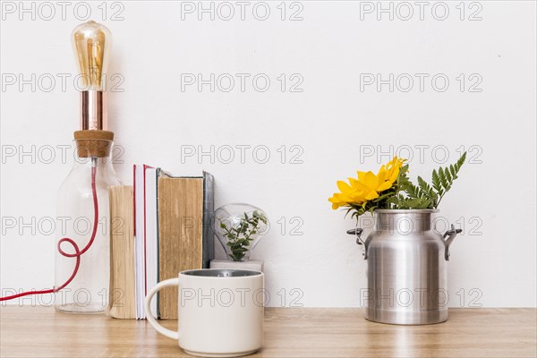 Cup flowers tin can books lamp table