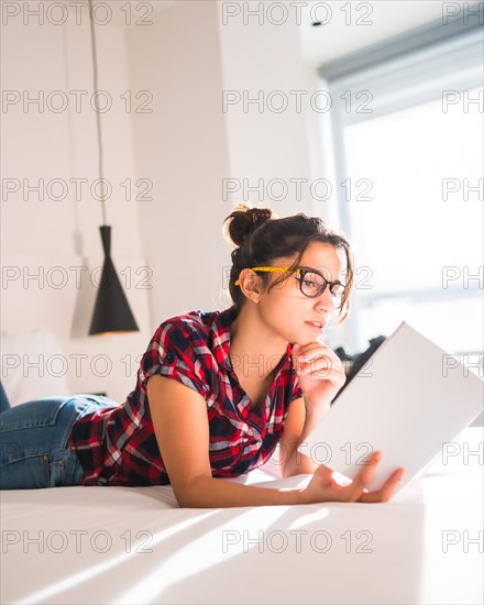 Side view of a beauty young woman reading an interest novel in an hotel room