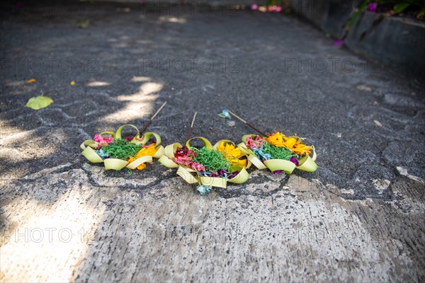 Three beautiful colourful opera bowls on the roadside. Flowers as an offering in Ubud