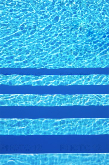Water surface with light reflections and pool stairs in a swimming pool