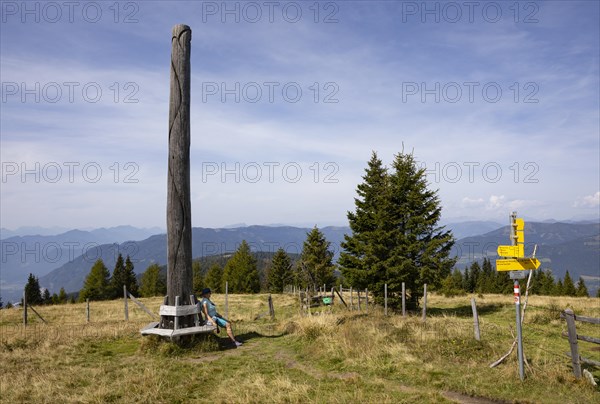 Wanderi sits by an artistic wooden sculpture on the Gerlitzen