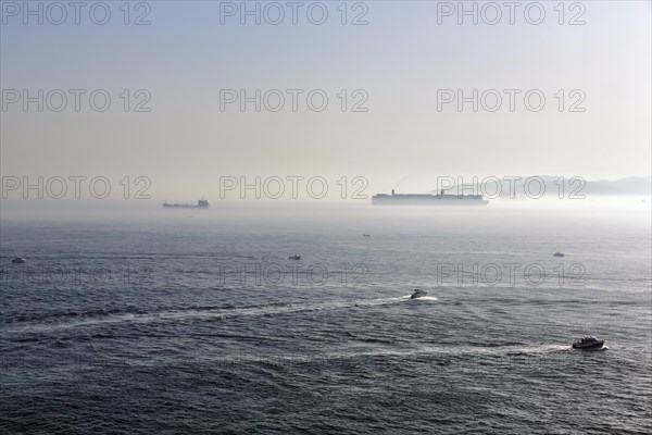 Cargo ships and motorboats in the haze