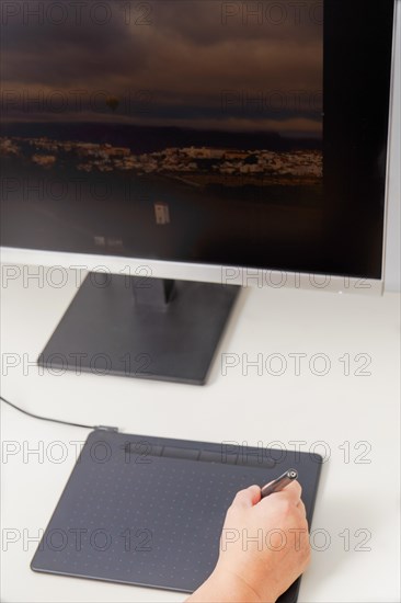 Woman hand working on her computer with a digital graphic tablet