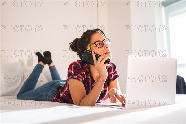 Young freelance talking to the mobile while working from the hotel room