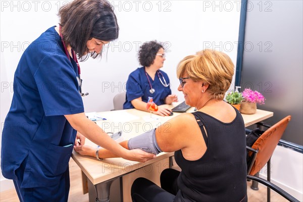 Nurse measuring the blood pressure to a woman patient