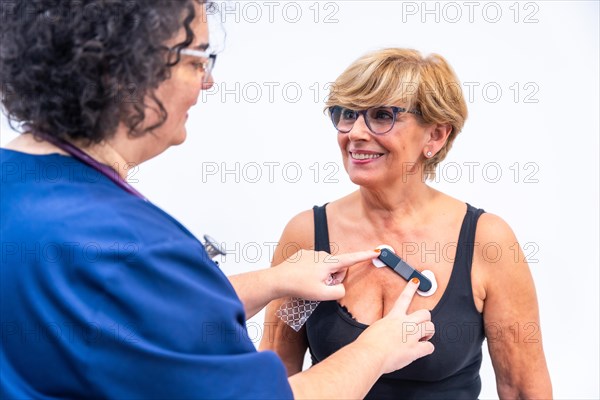 Female doctor putting woman with heart problems undergoing ECG Holter monitor test with innovative device on chest