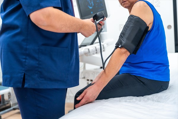 Doctor measuring the blood pressure of a woman sitting on a stretcher in a clinic room