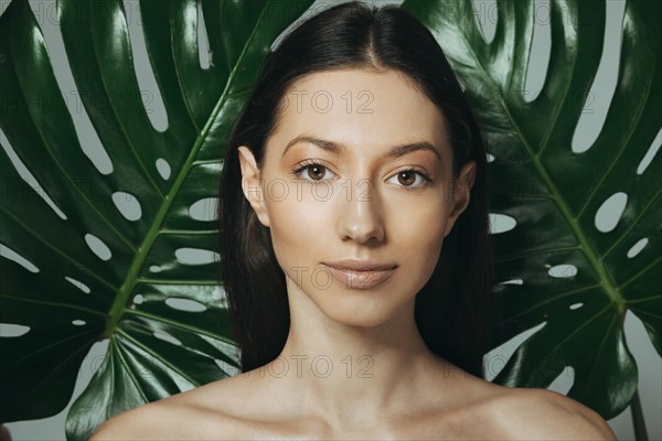 Brunette girl posing with exotic leaves